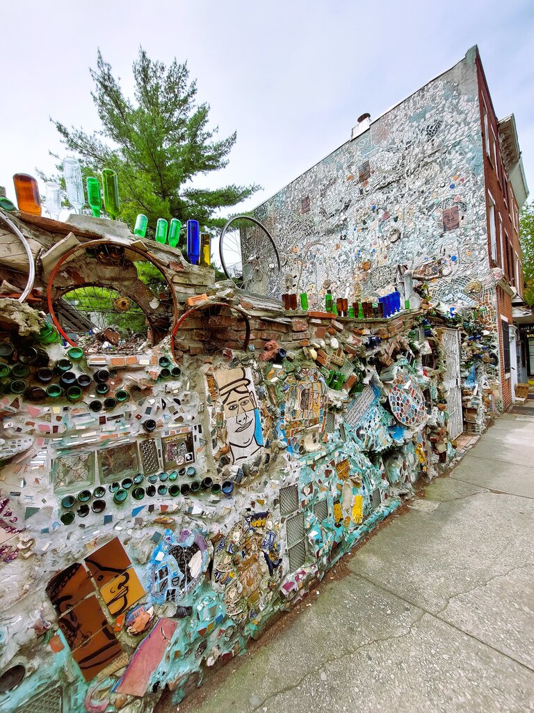 Eine künstlerisch gestaltete Mauer mit bunten Flaschen, Fahrradfelgen und Malereien des Mosaikkünstlers Isaiah Zagar im Philadelphia Mirror Garden | © Constanze Schwarz