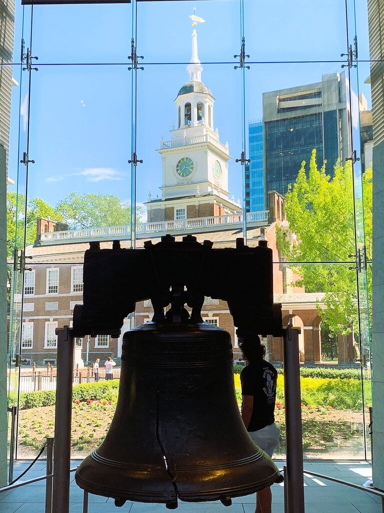 Blick über die Liberty Bell in einem Museum auf ein historisches Gebäude. Im Fokus steht die Liberty Bell | © Constanze Schwarz
