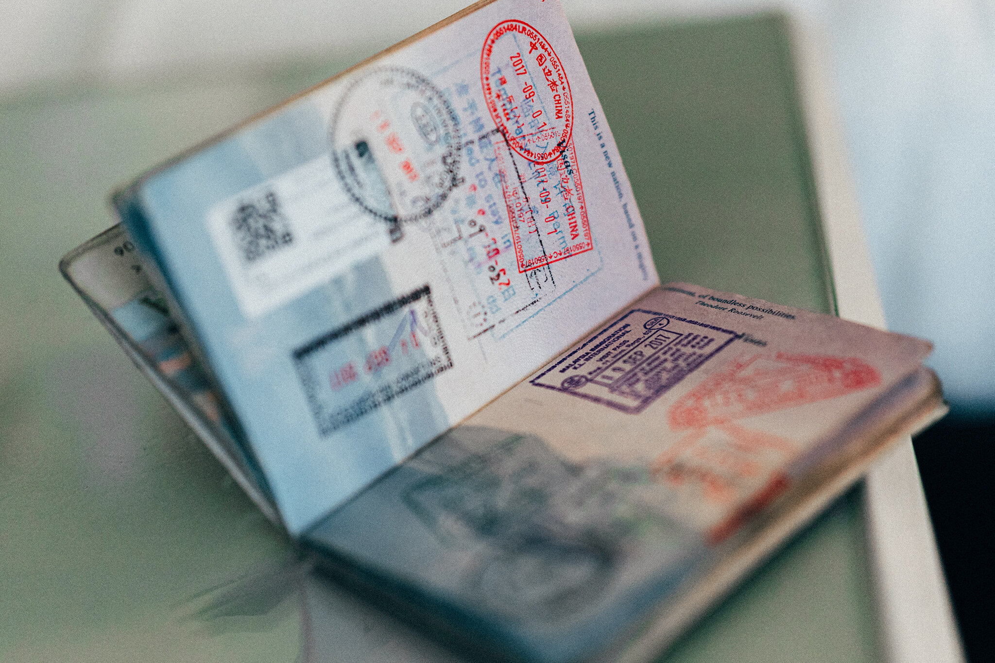 Auf einem Tisch liegt ein geöffneter Reisepass in dem verschiedene Visa-Stempel zu sehen sind. | © unsplash | convertkit